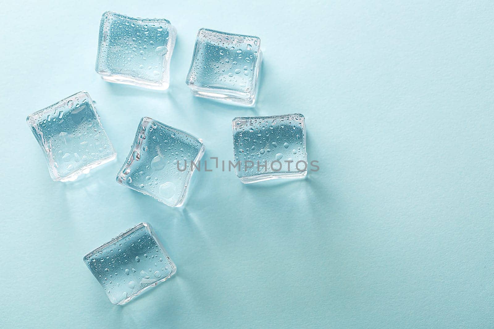 Ice cubes on vibrant light blue colors. Concept art. Minimal surrealism. Flat lay with copy space. Soft focus.