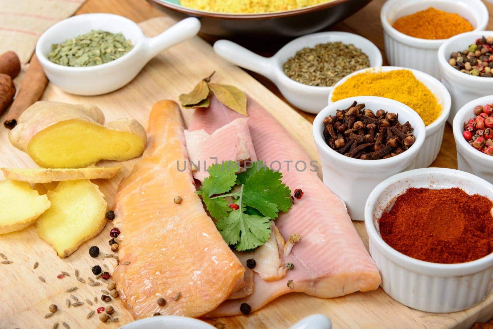 fish fillets with several spices on wooden table