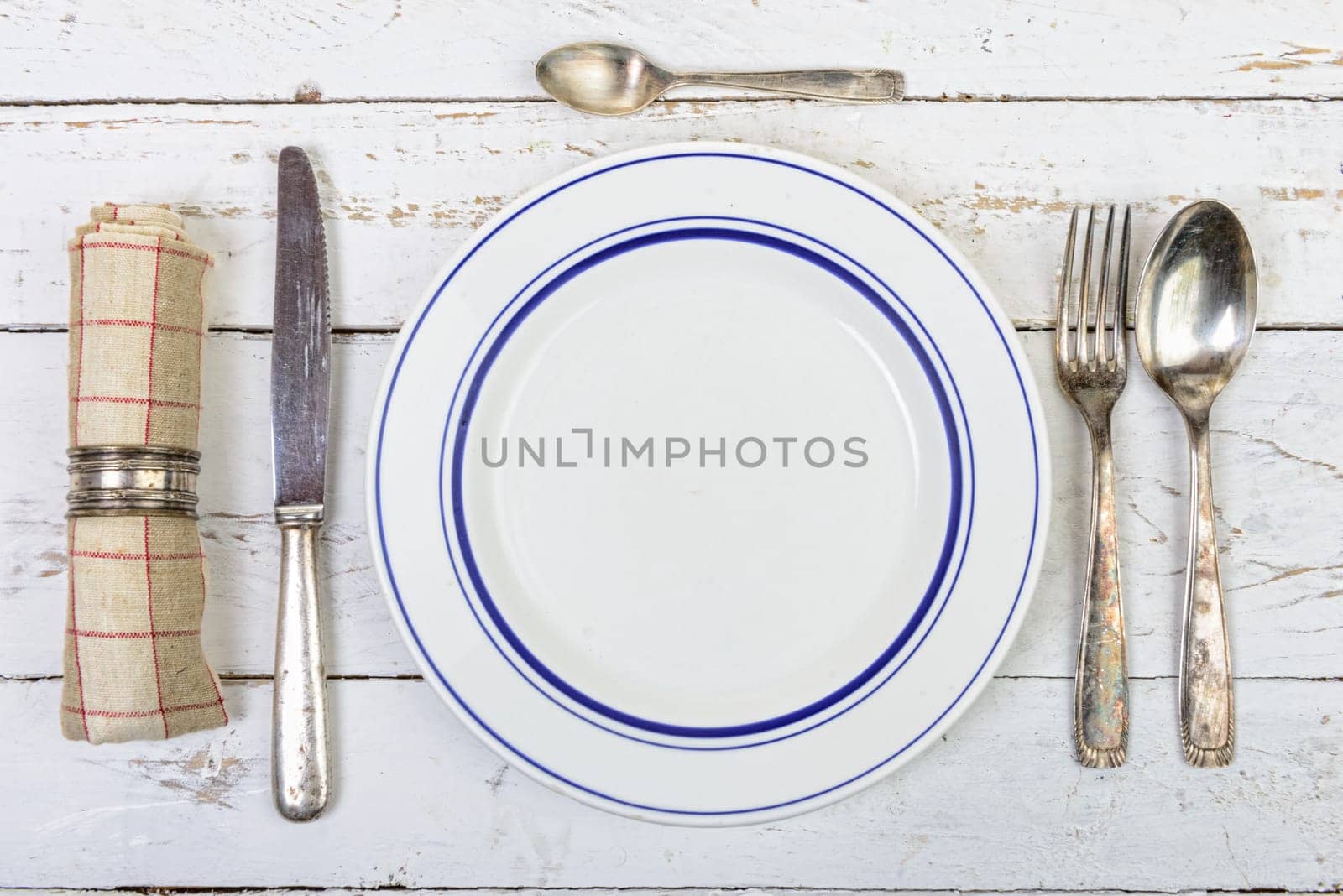 plate with silver cutlery on an old white table