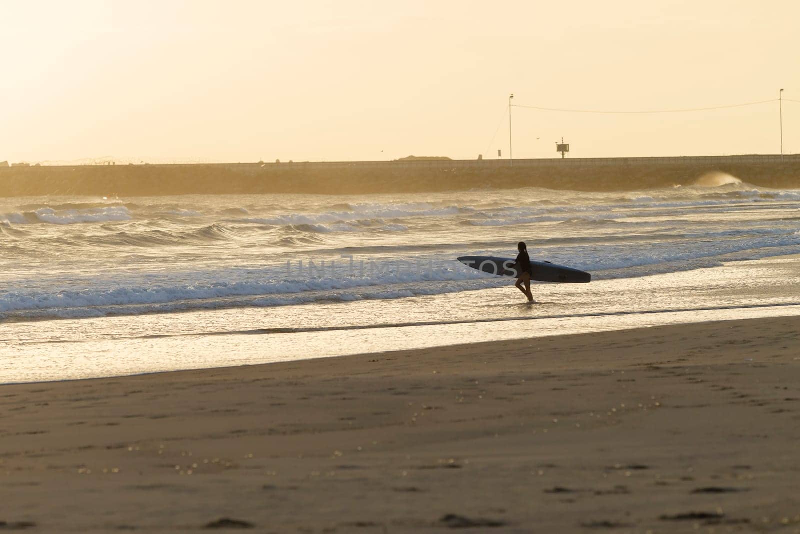 Teen girl athlete trains dawn sunrise on lifesaving rescue craft paddling out through ocean wave swells.