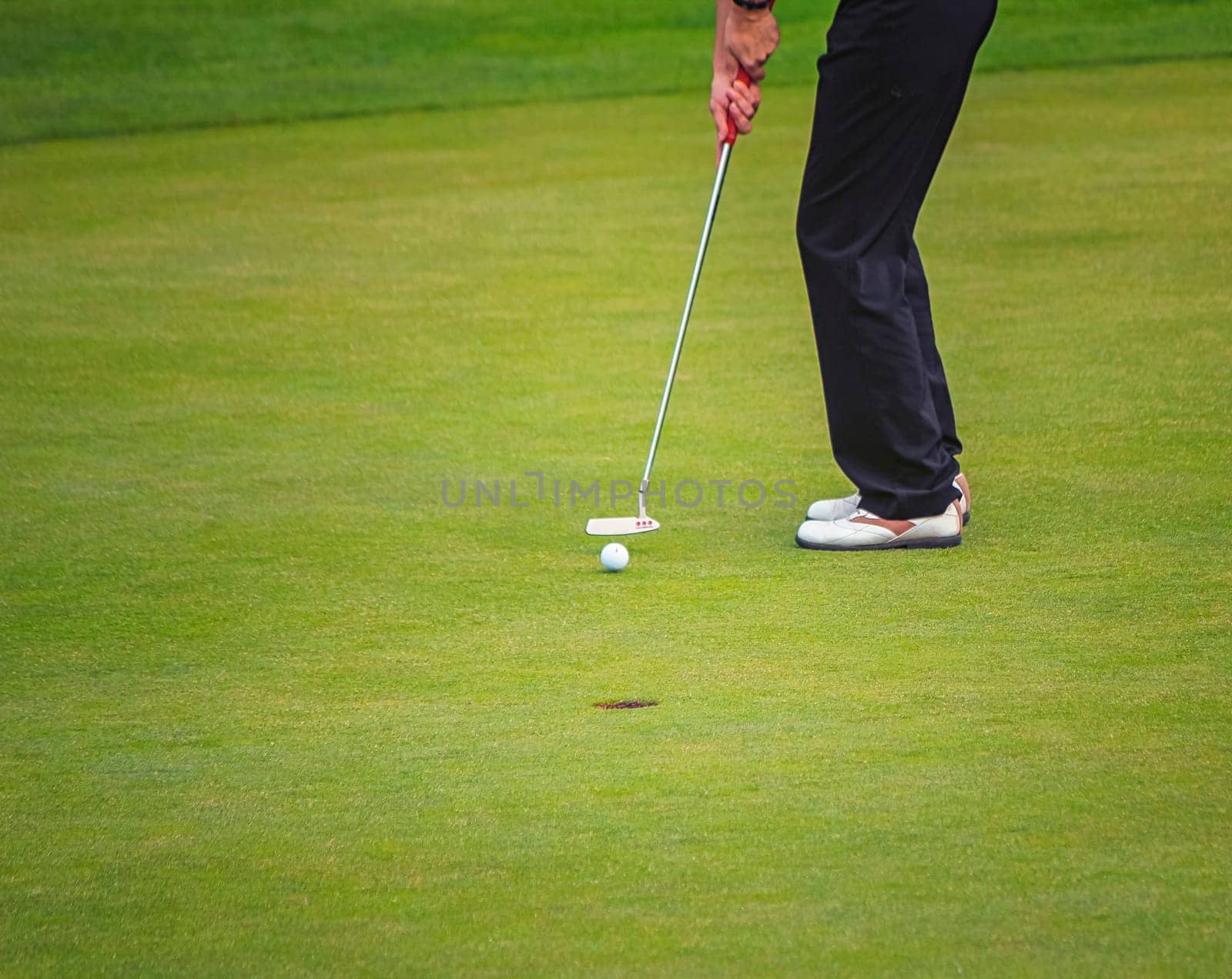 Golf player legs putting on the green