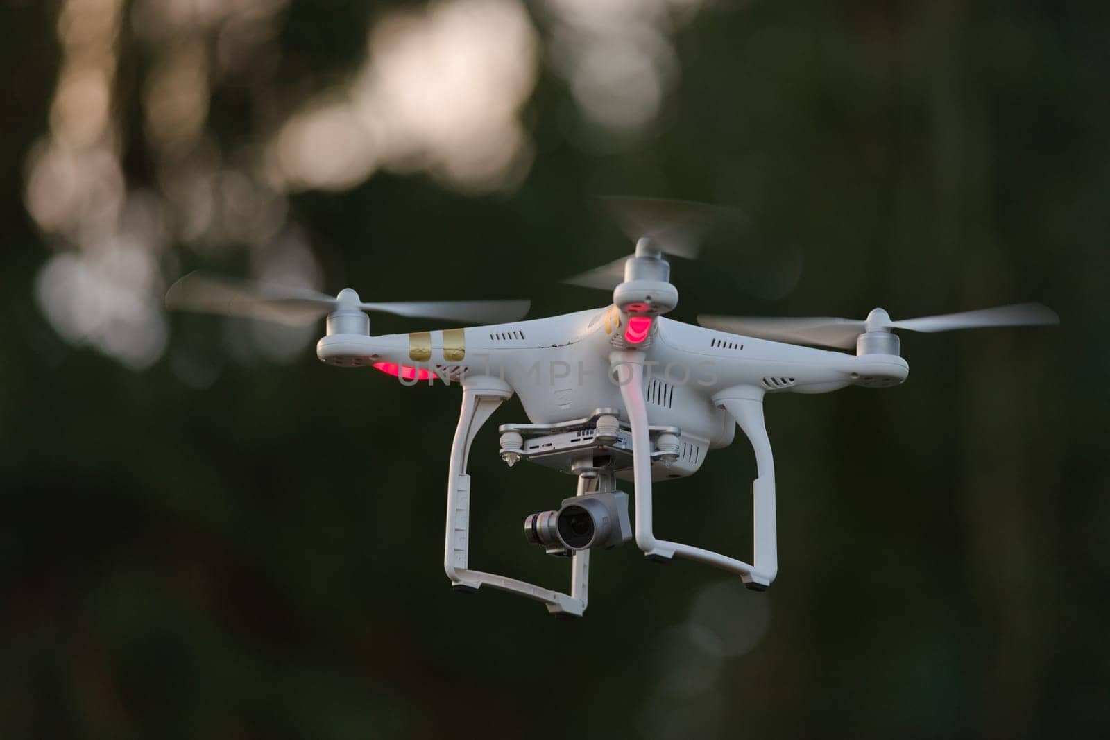 13 - Propellers spinning as this quadcopter drone hovers with camera payload. First person view flying capable, with cinematic videography usage.