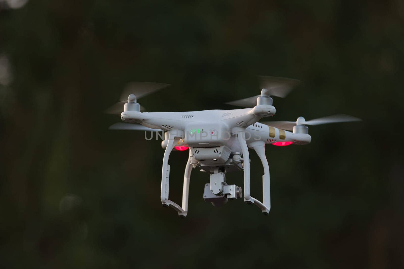 24 - White quadcopter surveillance video drone with dark background. Isolated subject using selective focus also stands out due to light color.