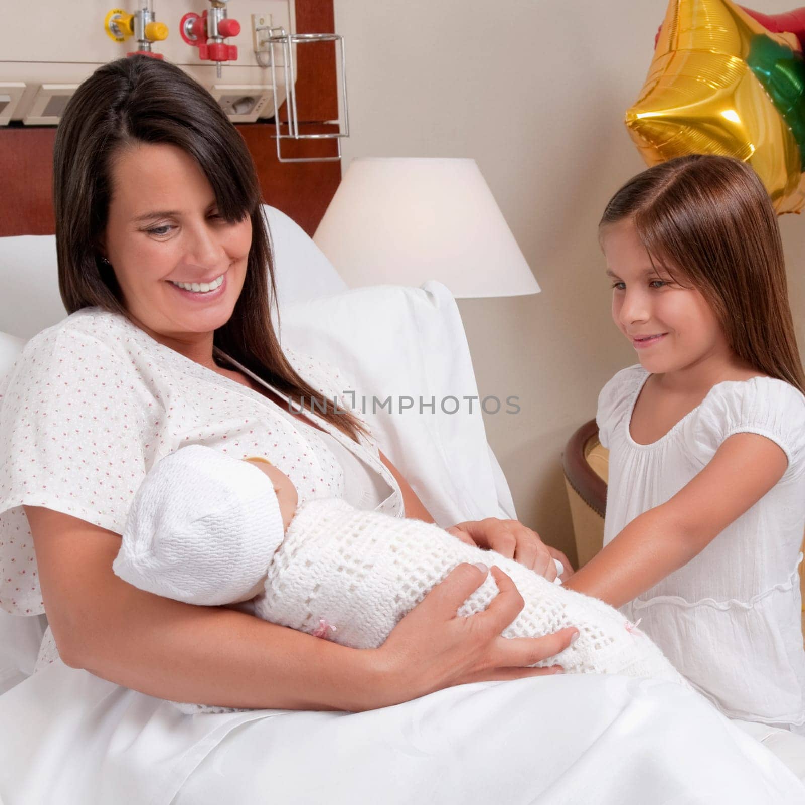 Woman carrying her newborn baby with her daughter in a hospital