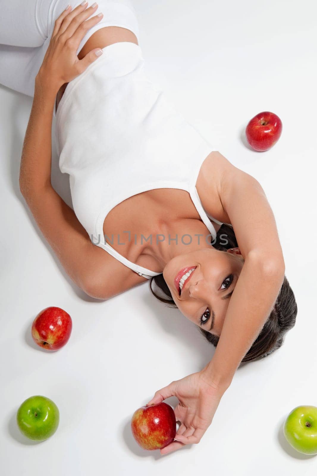 High angle view of a woman lying with red and green apples