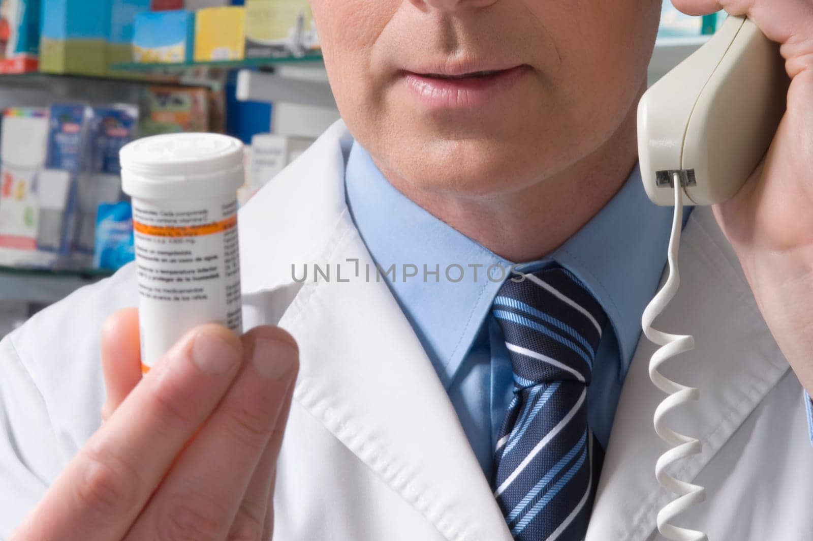Pharmacist holding a medicine bottle and talking on the telephone