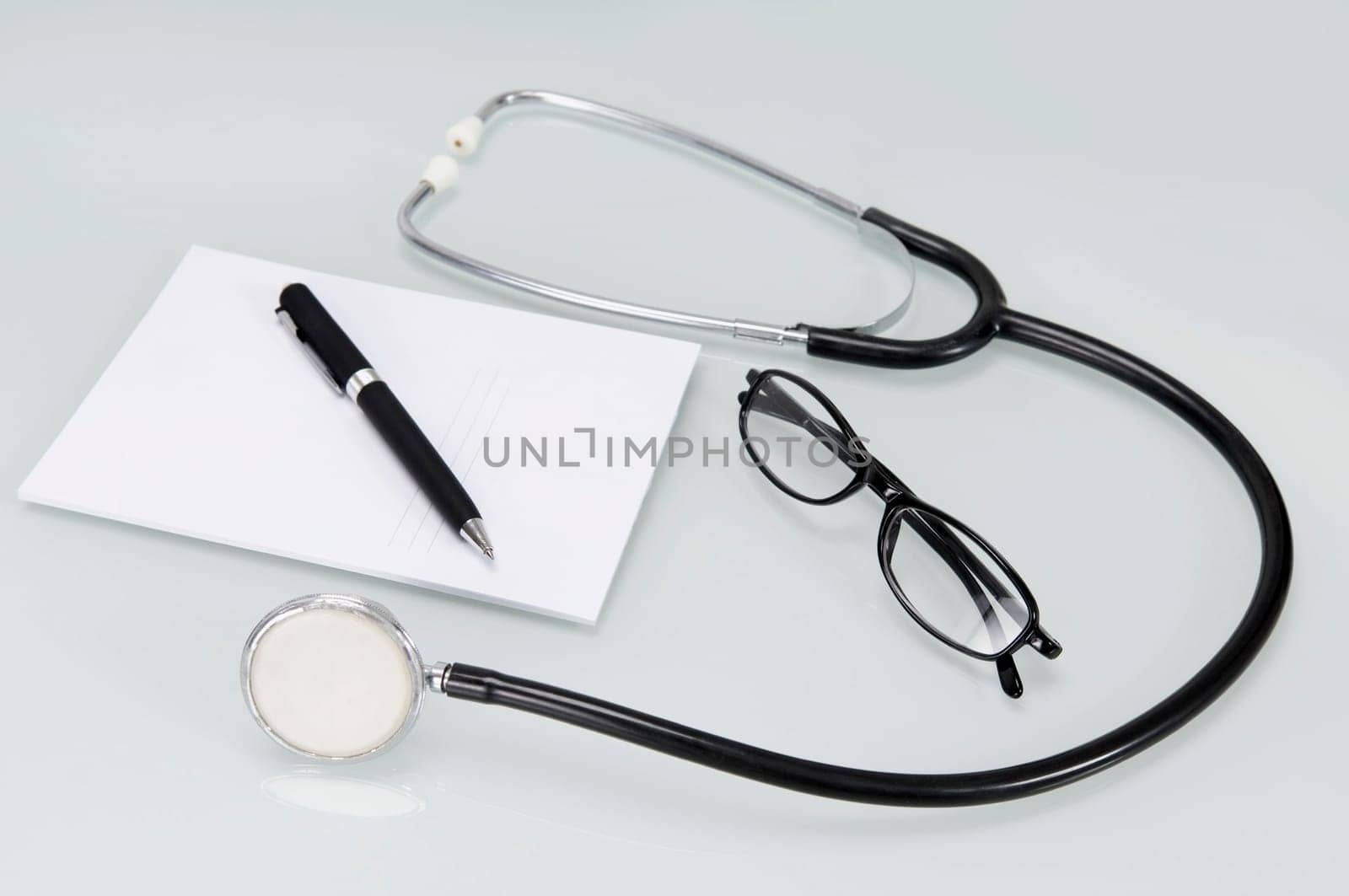 Close_up of a stethoscope with pen and prescription pad