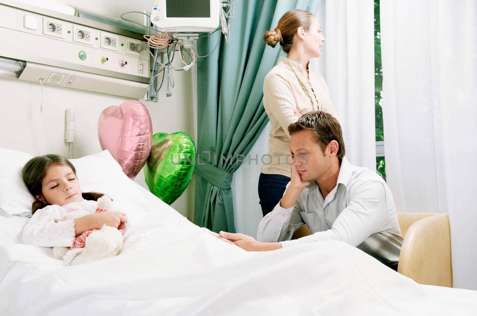 Girl on a hospital bed with her parents beside her