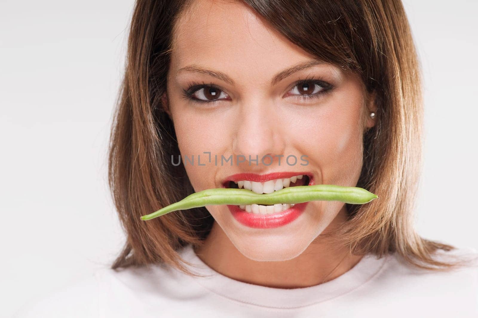 Woman holding stalk of bean between her teeth