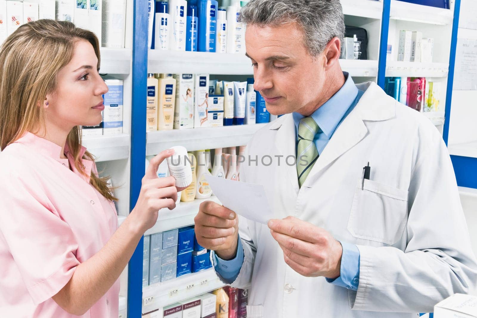 Female pharmacist showing a medicine bottle to a male pharmacist