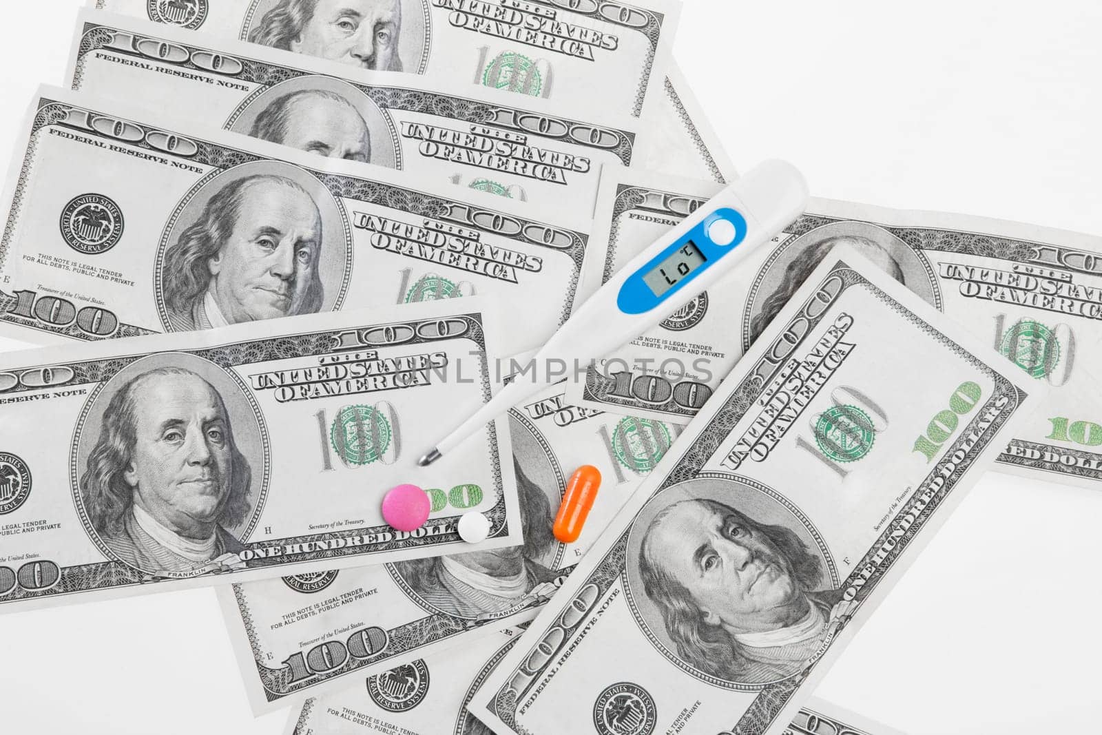 Close_up of hundred dollar bills with pills and a thermometer