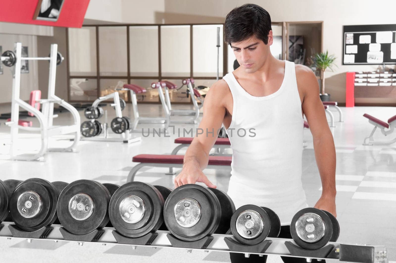 Man choosing dumbbells in a gym