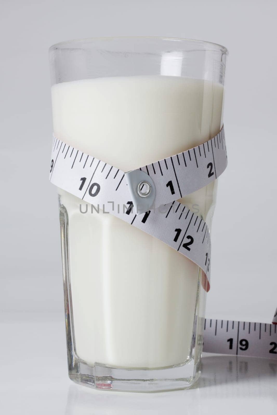 Close_up of a tape measure around a glass of milk
