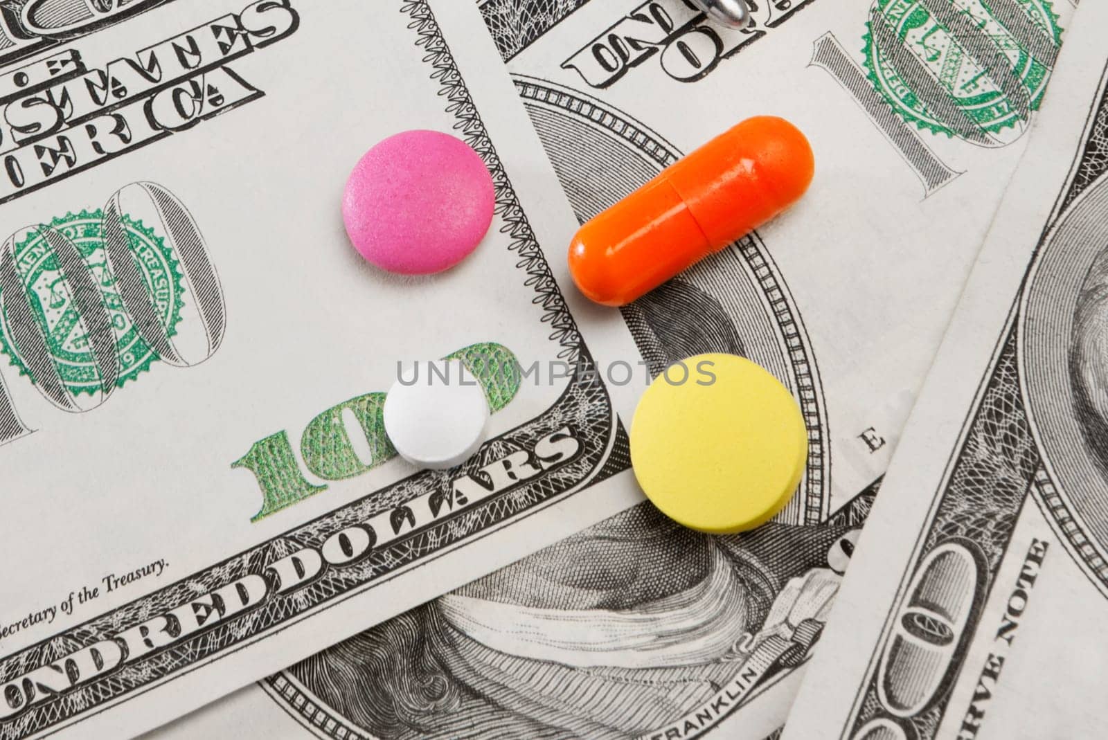 Close_up of pills on hundred dollar bills