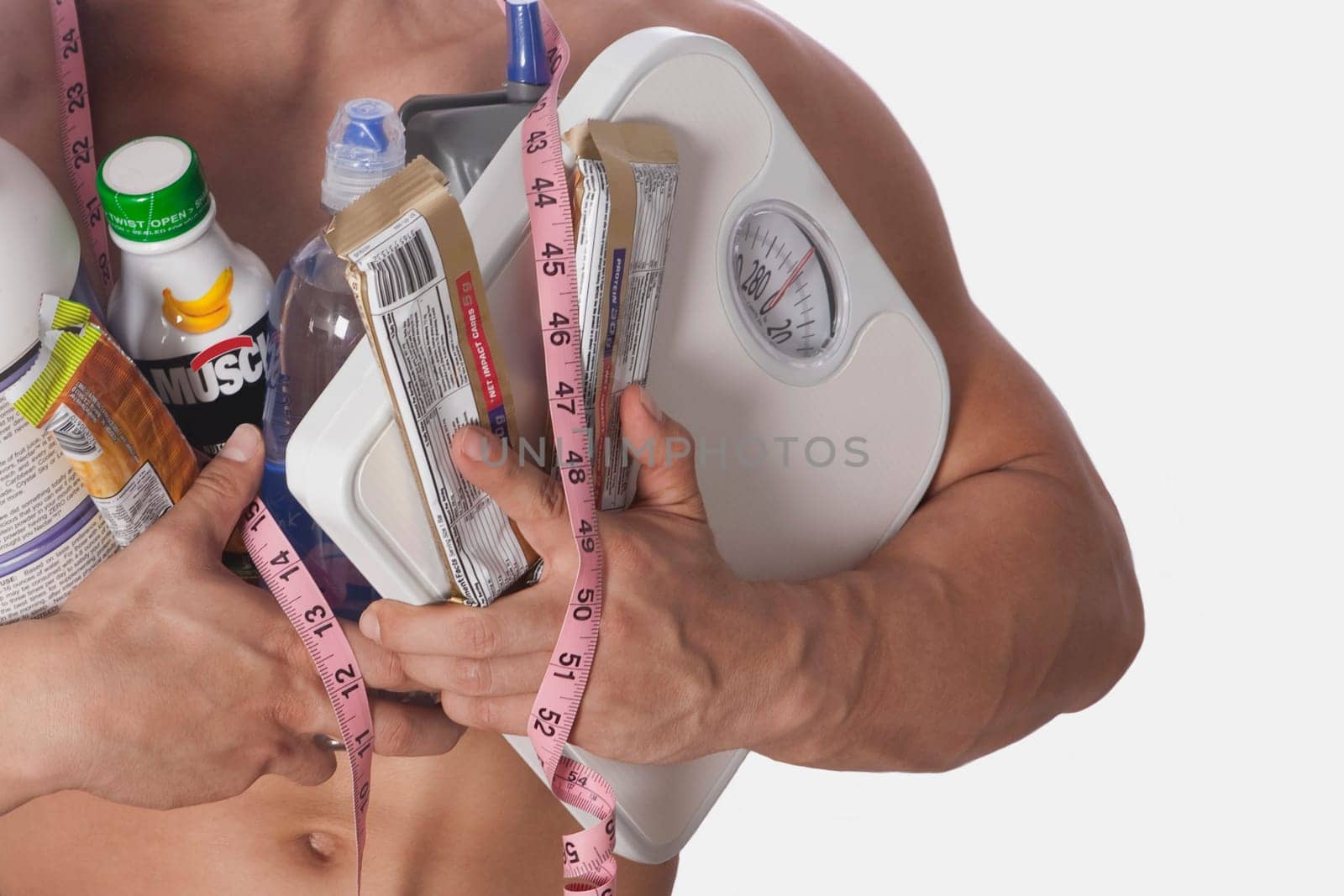 Mid section view of a man holding food supplements and a bathroom scale