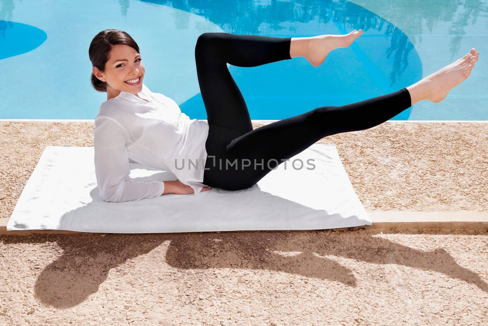 Woman practicing yoga at the poolside
