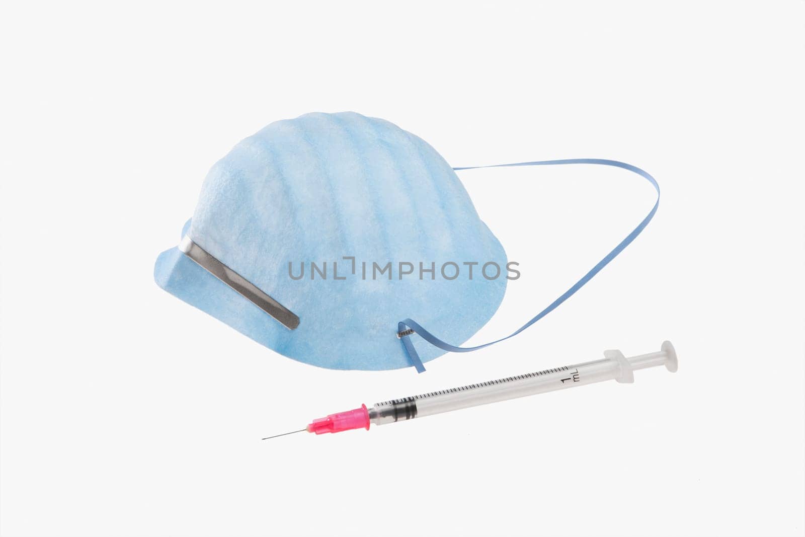 Close_up of a syringe and a swine flu mask