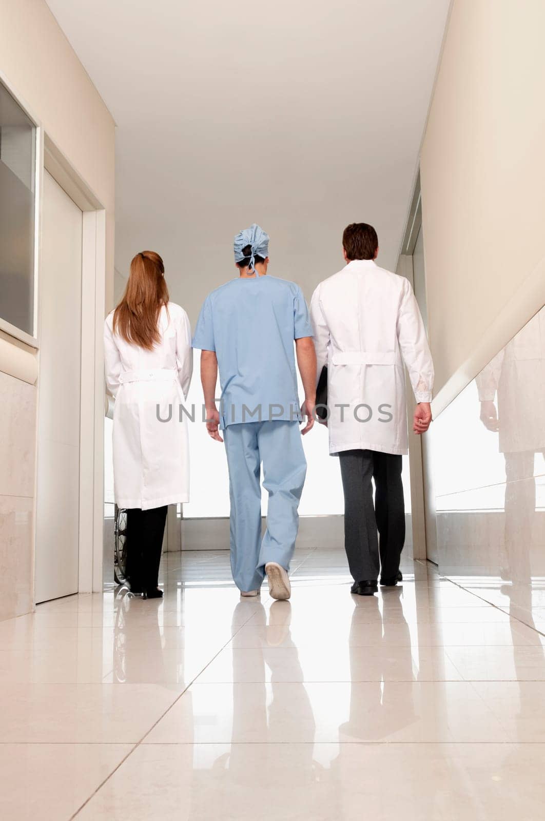 Rear view of three doctors walking in a hospital corridor