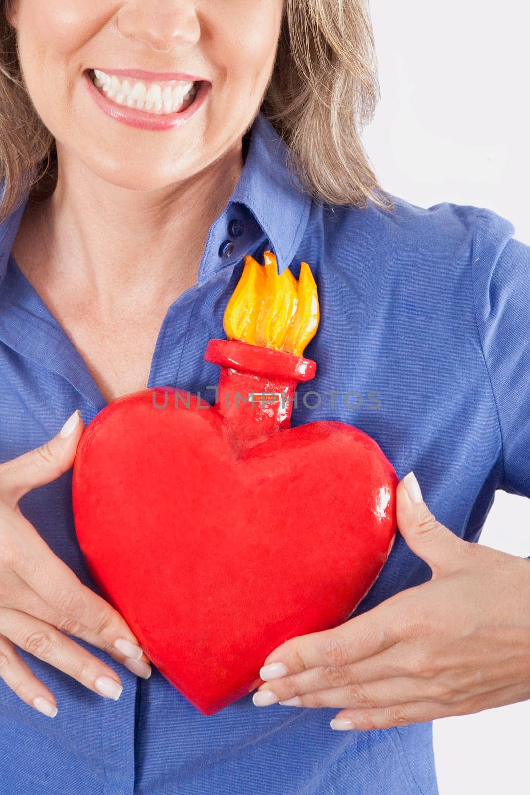Woman holding an artificial burning heart against her chest and smiling