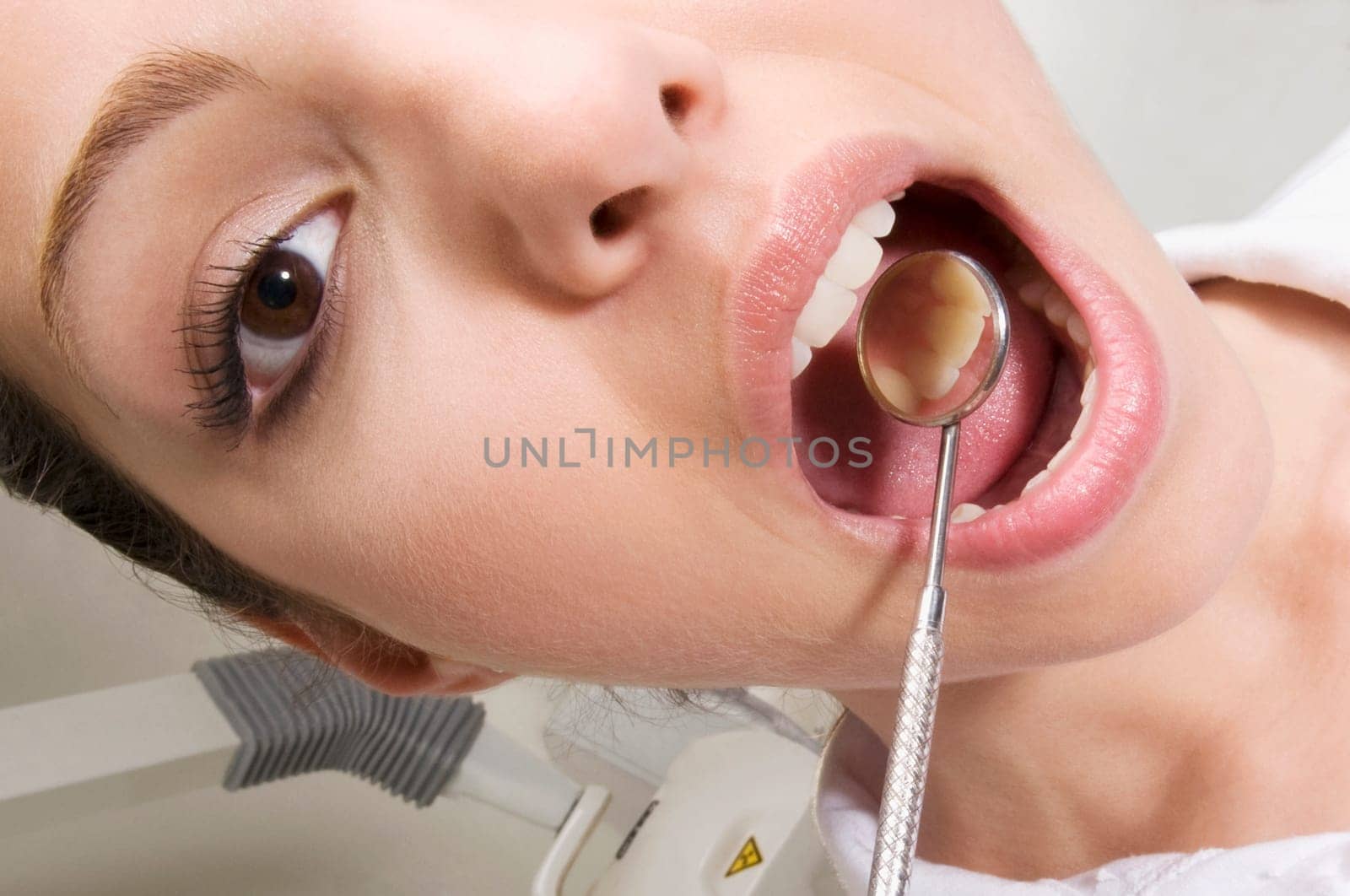 Woman examining her teeth with angled mirror