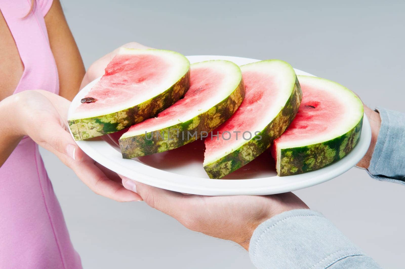Couple holding a plate of watermelon slices