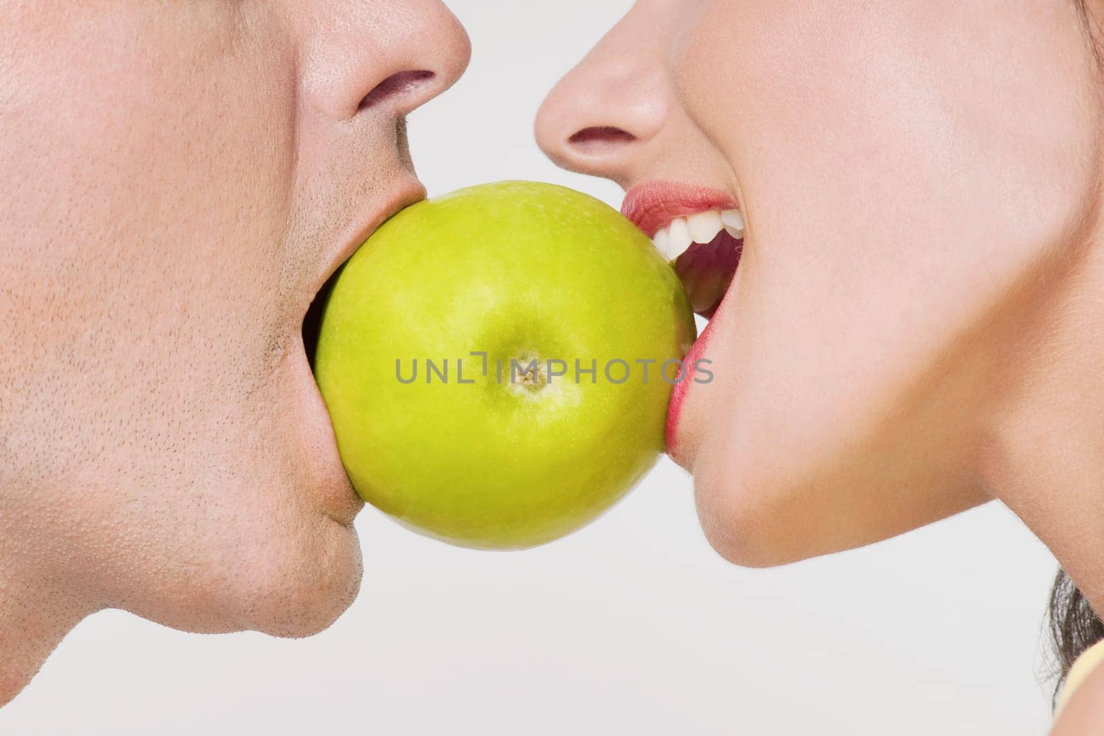 Couple biting into a green apple
