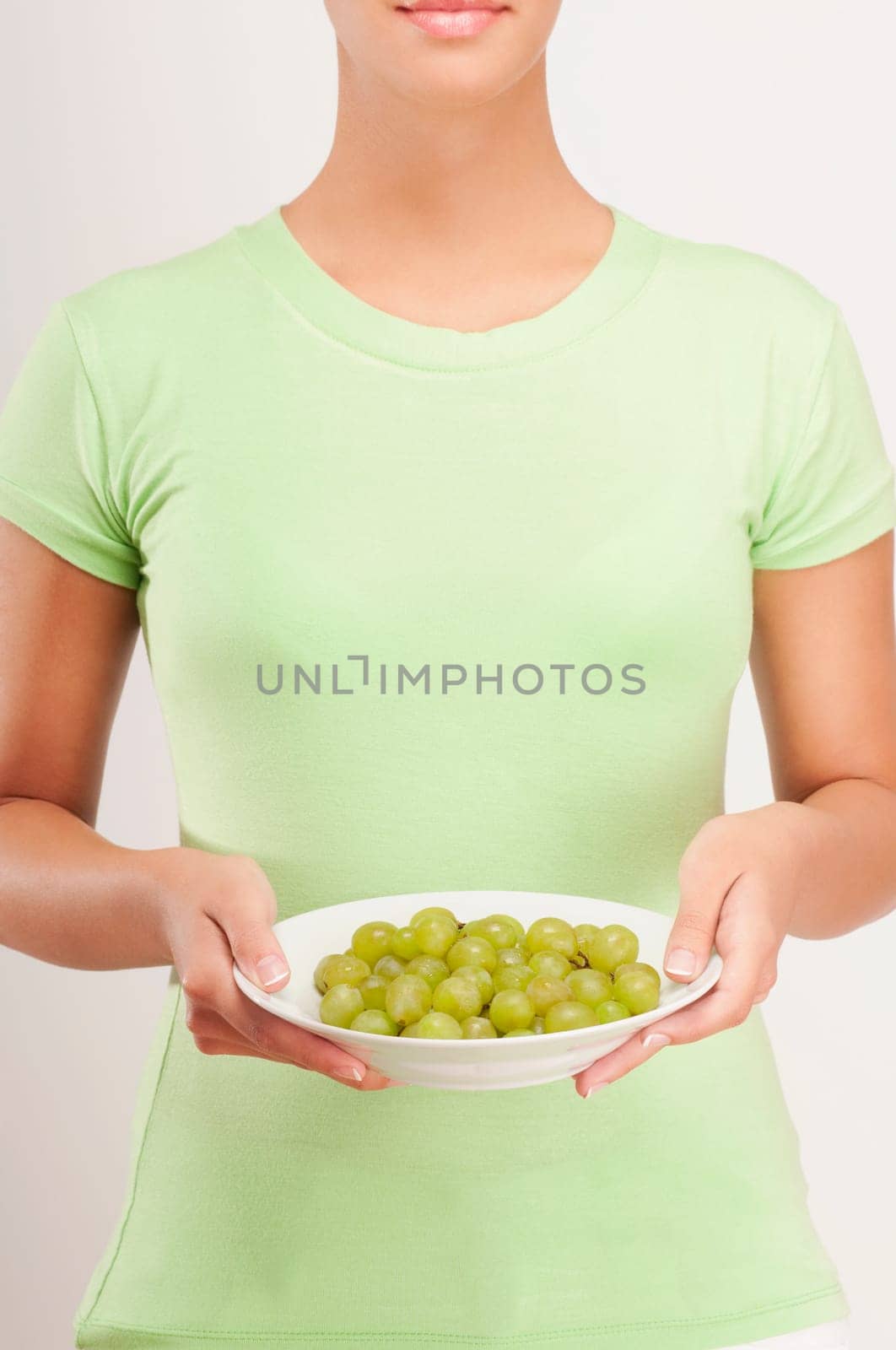 Mid section view of a woman holding a bowl of grapes