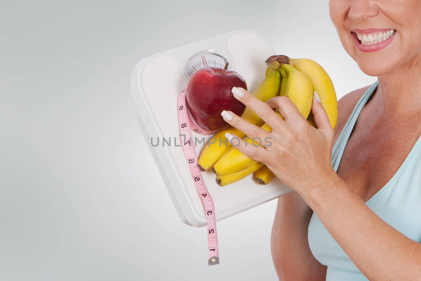 Woman holding a bathroom scale and fruits