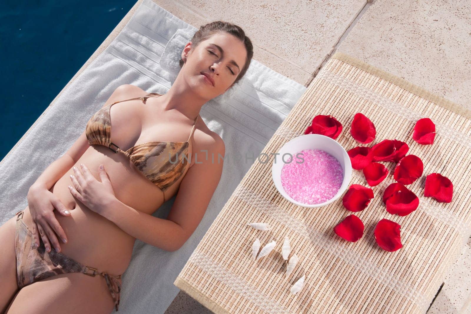 Woman resting with aroma products beside her at the poolside