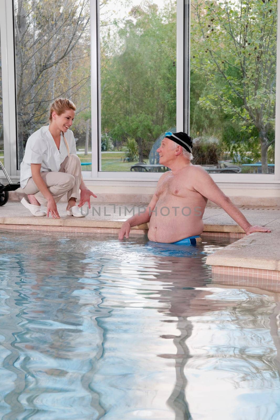 Man in a swimming pool and talking to a health worker