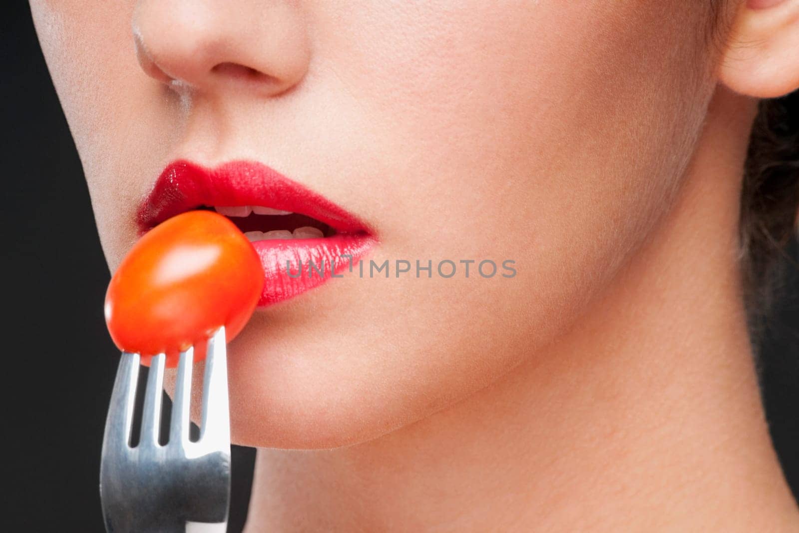 Close_up of a woman eating a cherry tomato