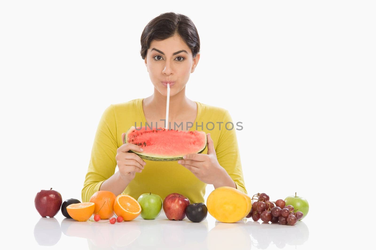 Portrait of a woman drinking from a watermelon with a straw
