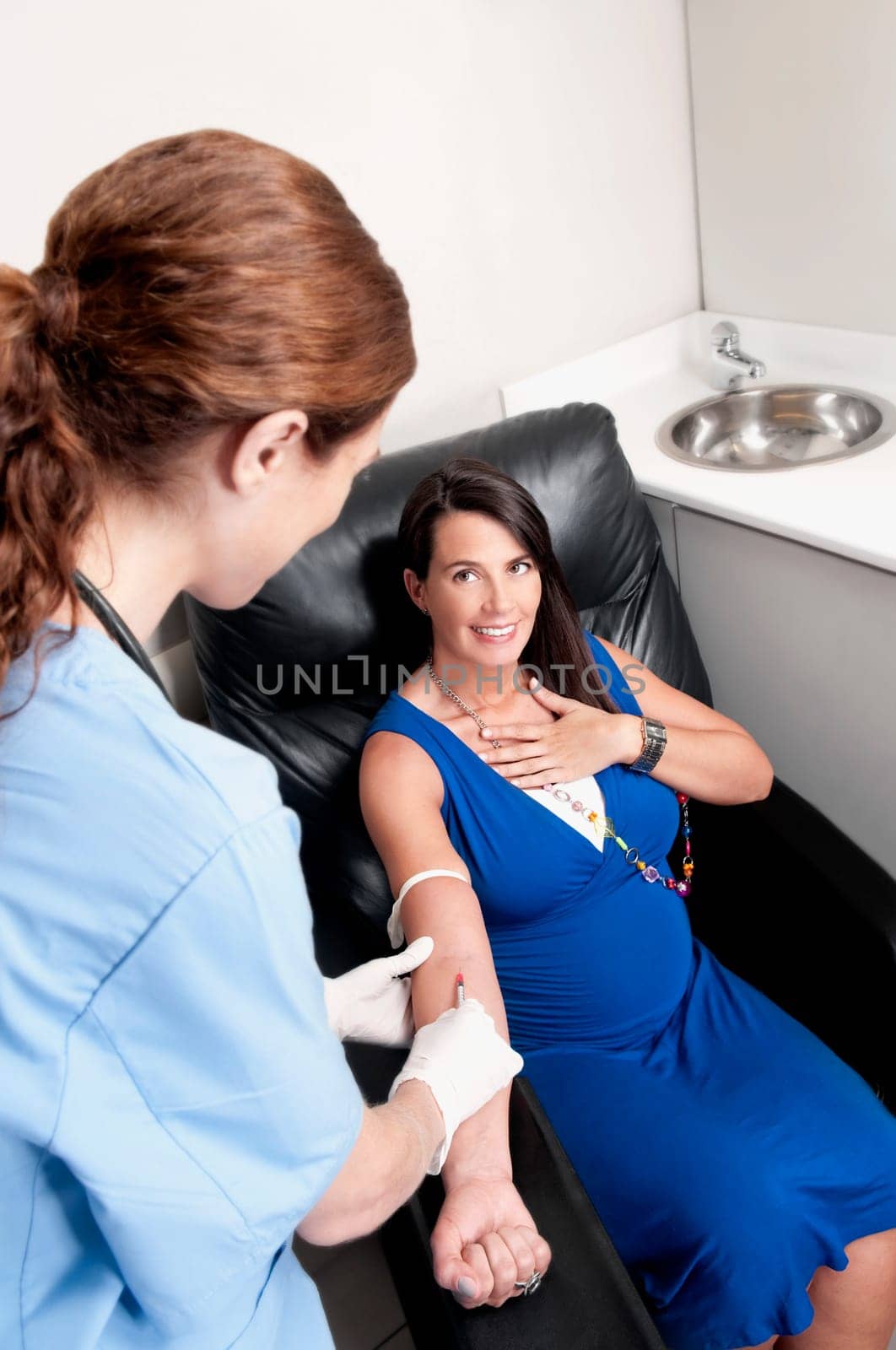 Female doctor taking blood sample of a pregnant woman