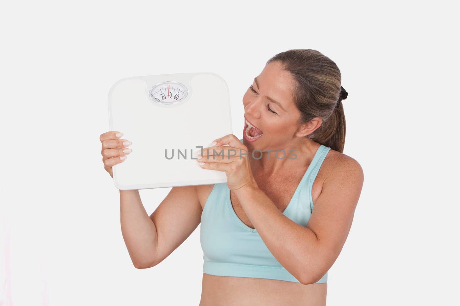 Close_up of a woman holding a bathroom scale and looking excited