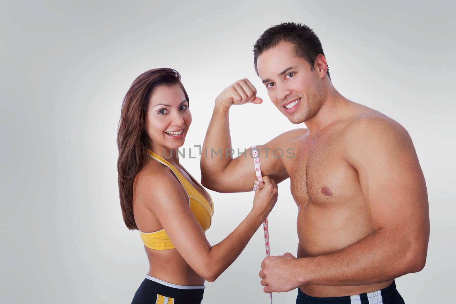 Woman measuring biceps of a man with a tape measure