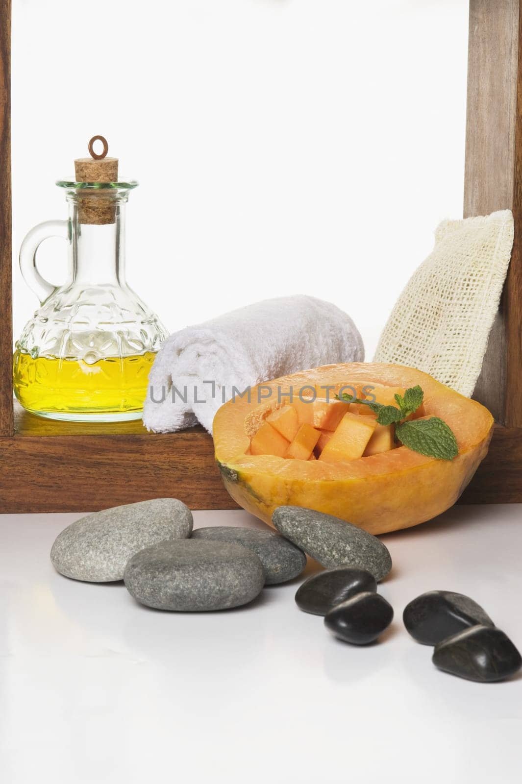 Close_up of papaya with body oil and spa stones