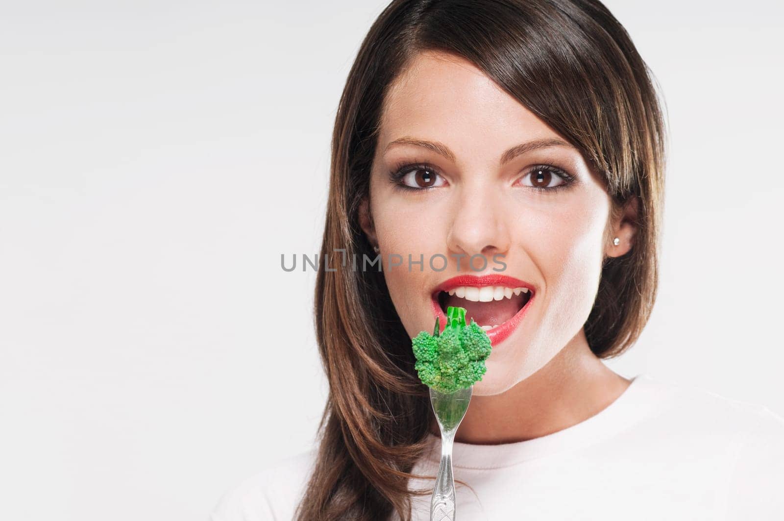 Portrait of a woman eating broccoli