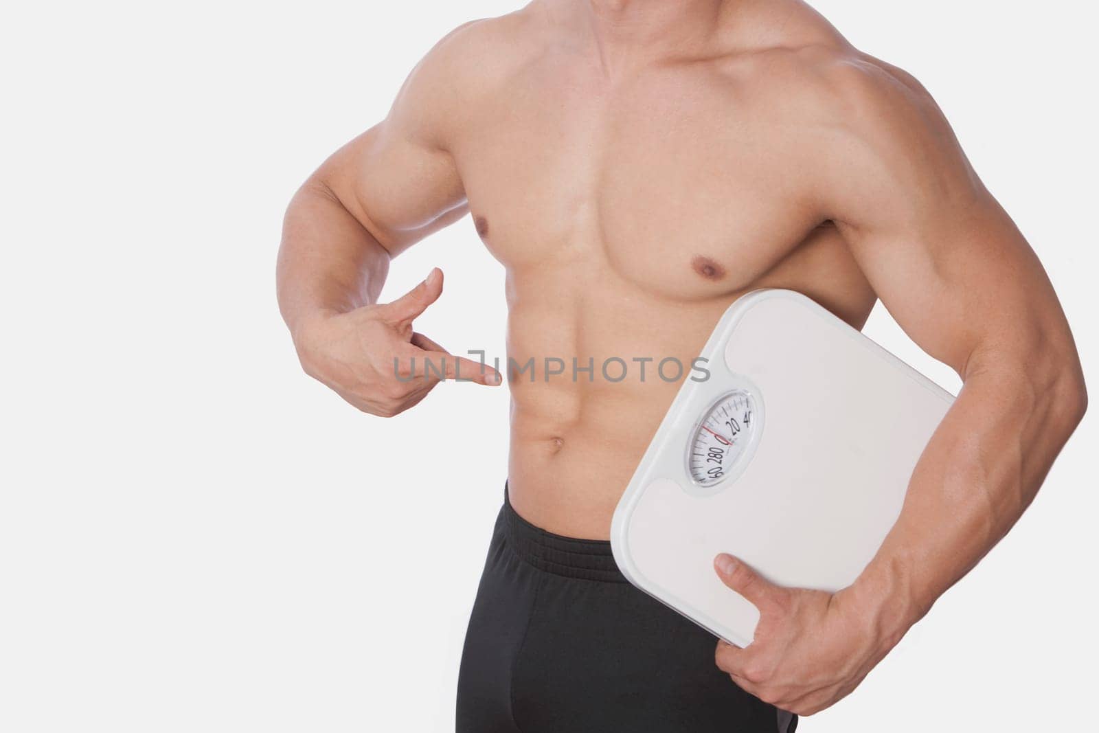 Mid section view of a man holding a bathroom scale and showing his abdomen