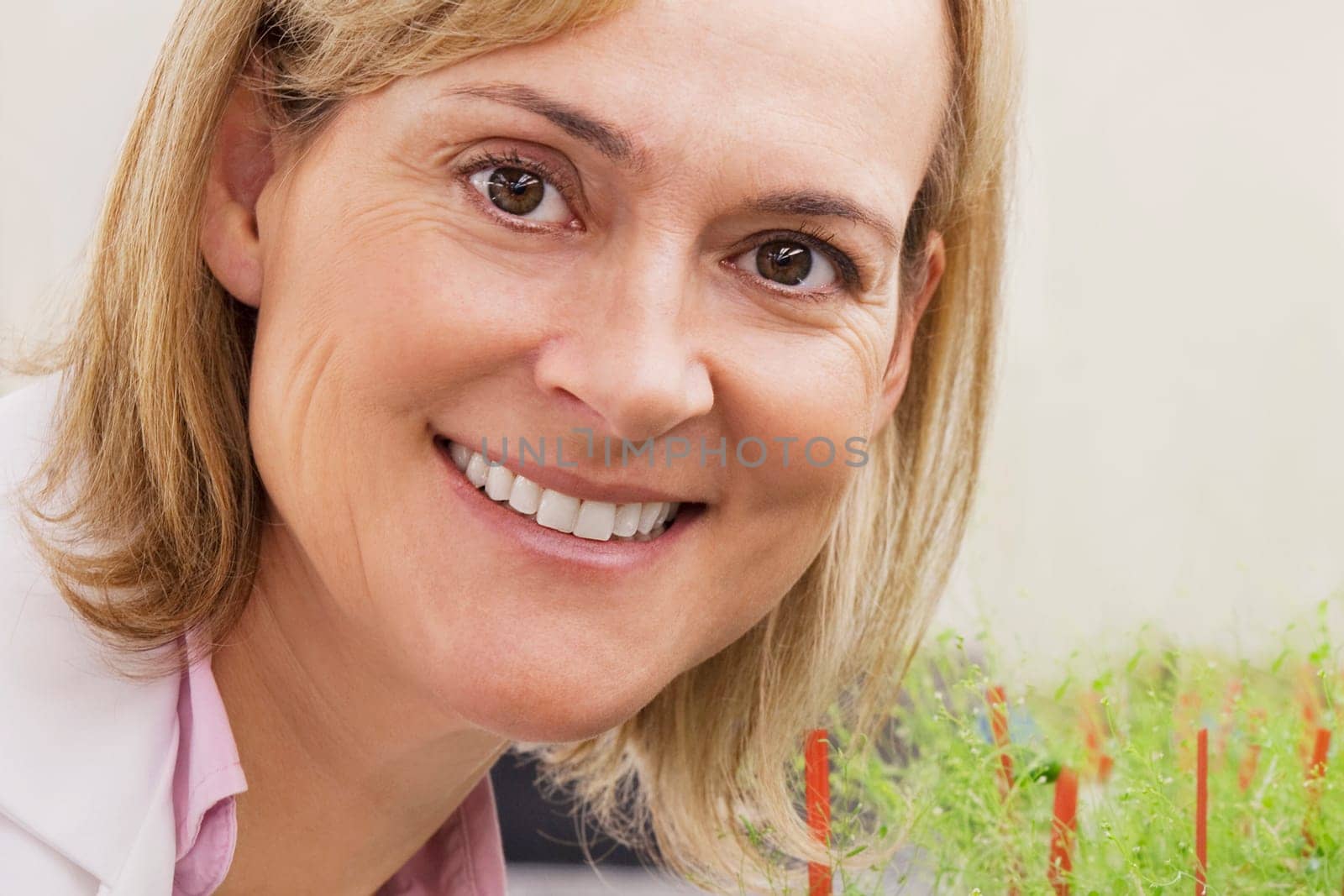Female scientist smiling near plants in a laboratory