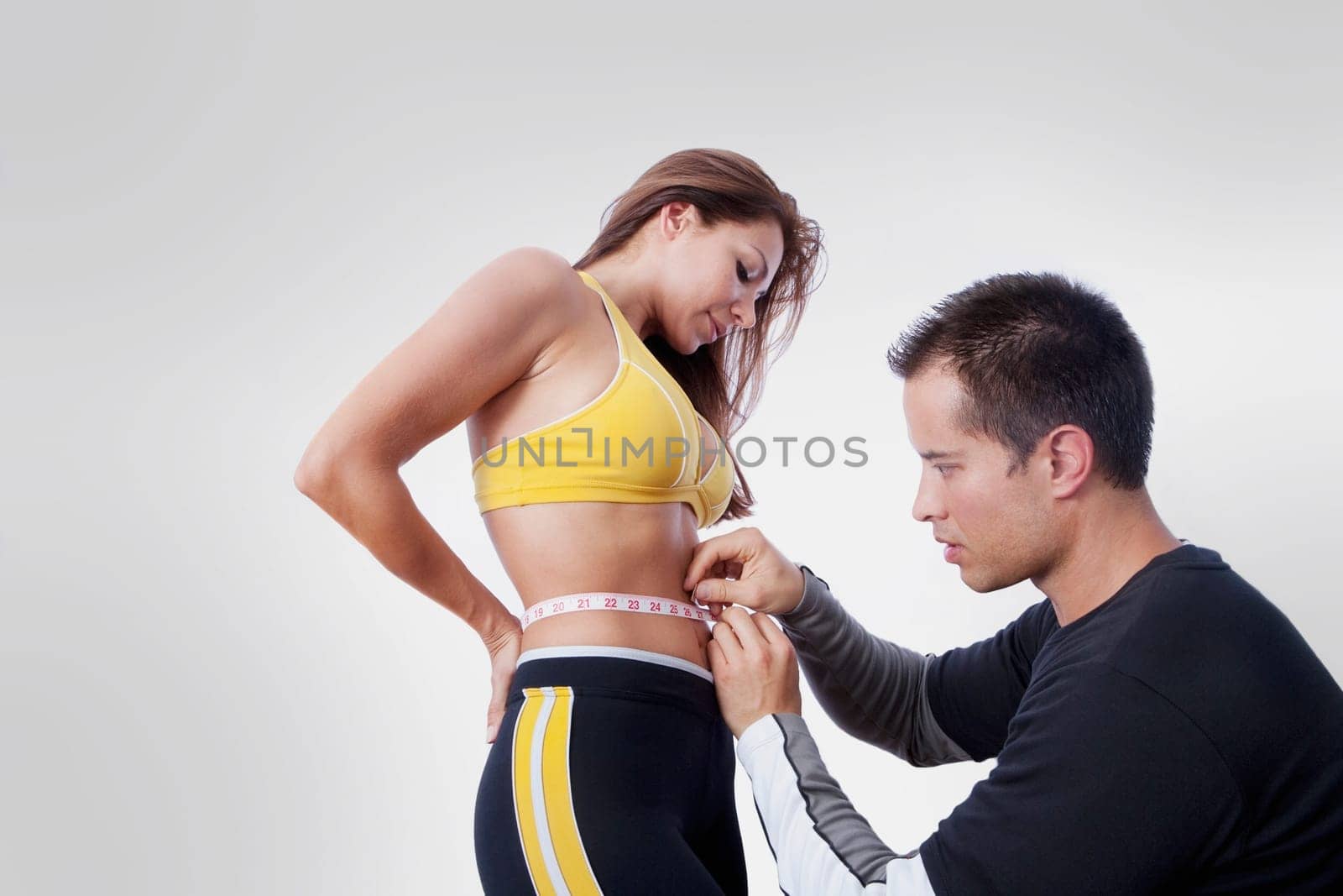 Man measuring the waist of a woman with a tape measure