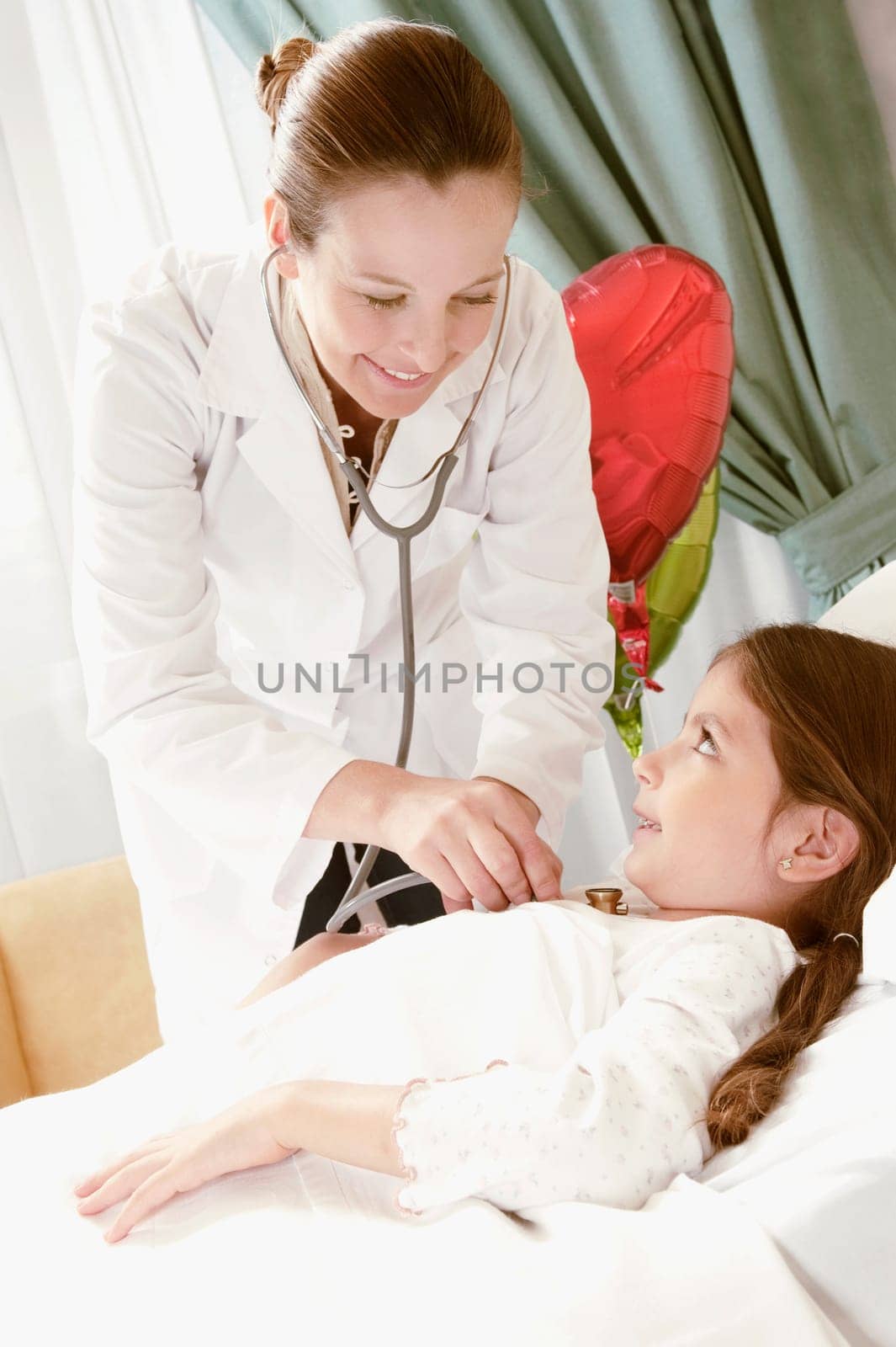 Girl on a hospital bed being examined by a female doctor