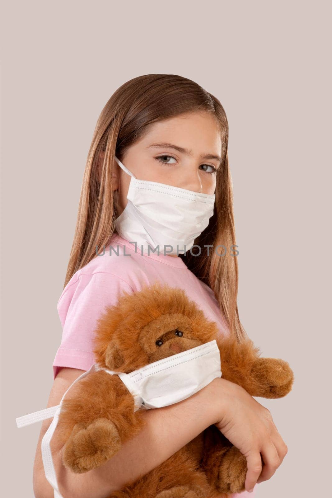 Girl wearing flu mask and holding a teddy bear