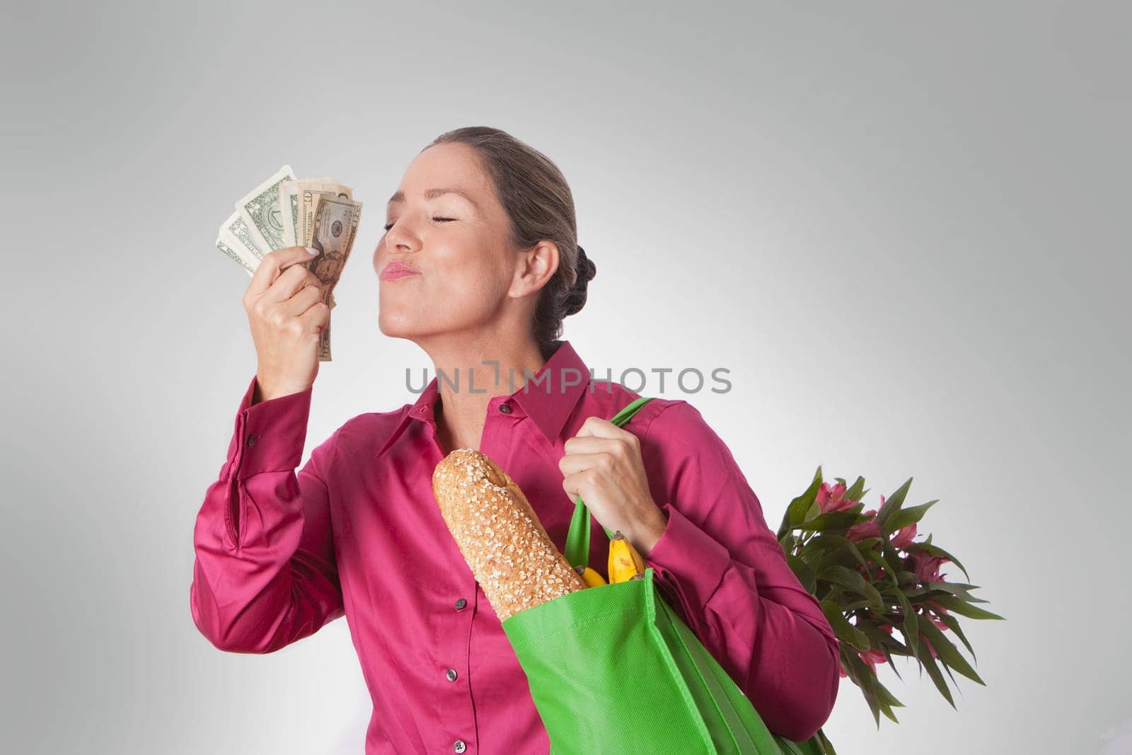 Woman holding a shopping bag of groceries and currency notes