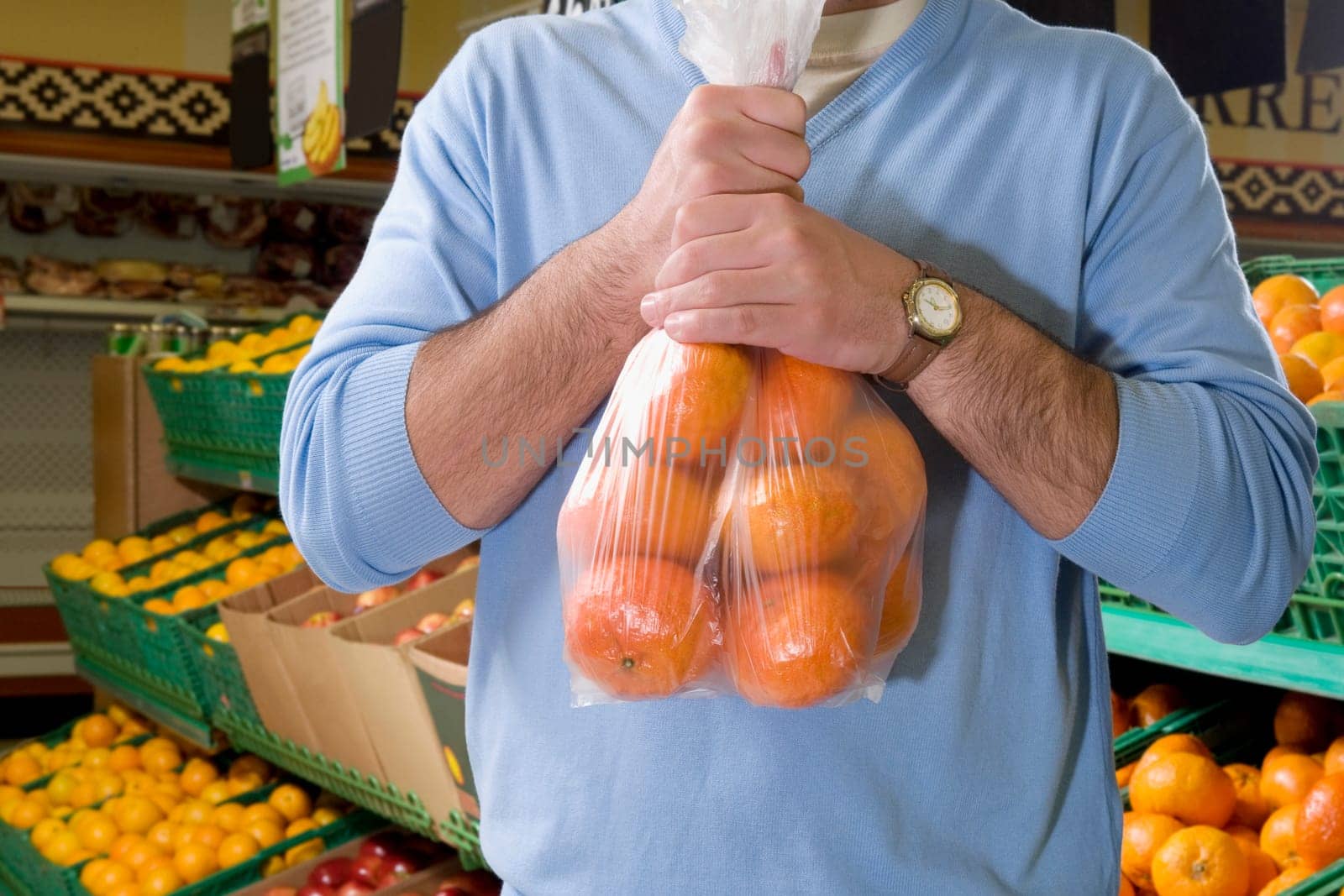 Mid section view of a man holding oranges in a supermarket