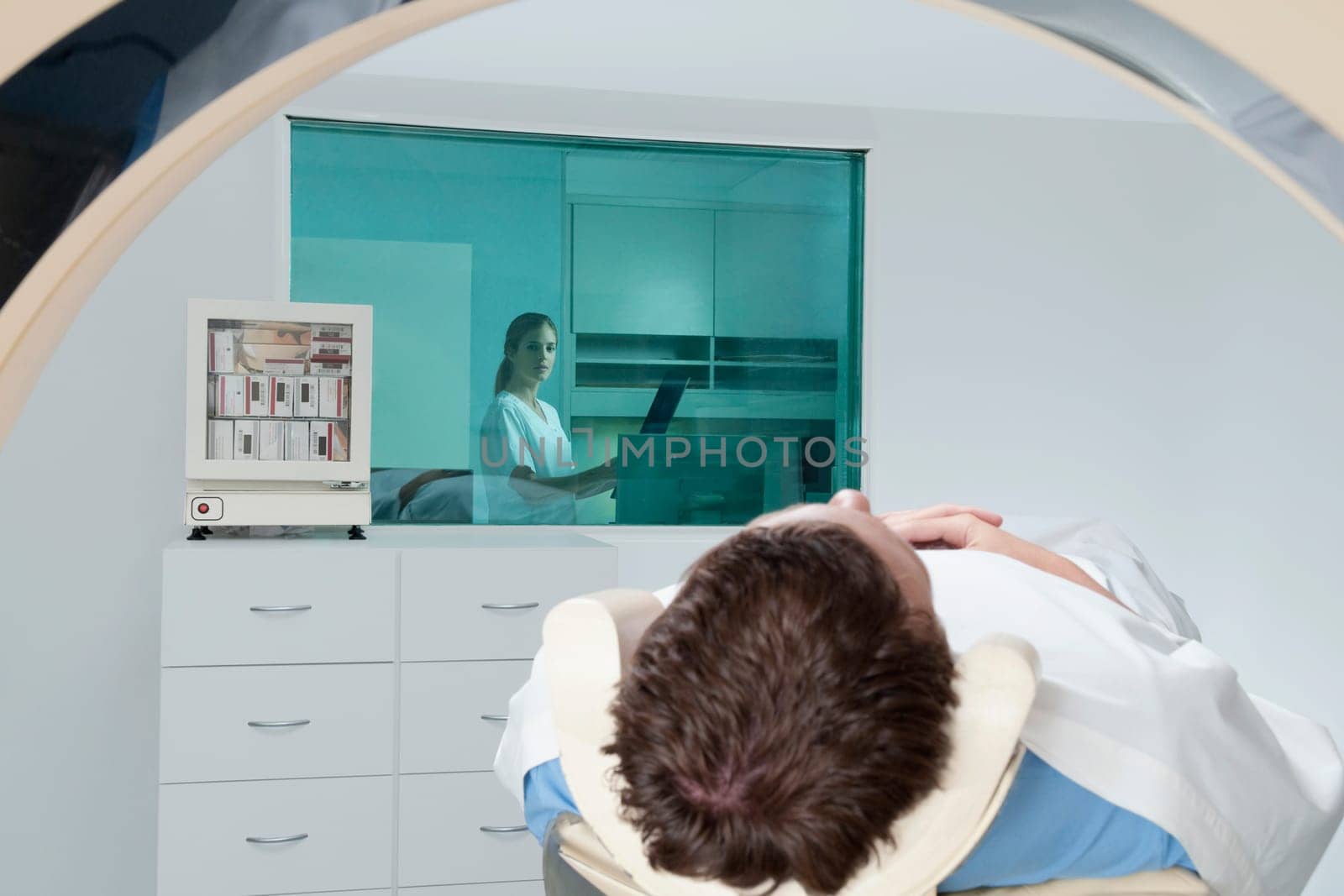 Patient going through an MRI scan with a doctor analyzing an X_Ray report in background