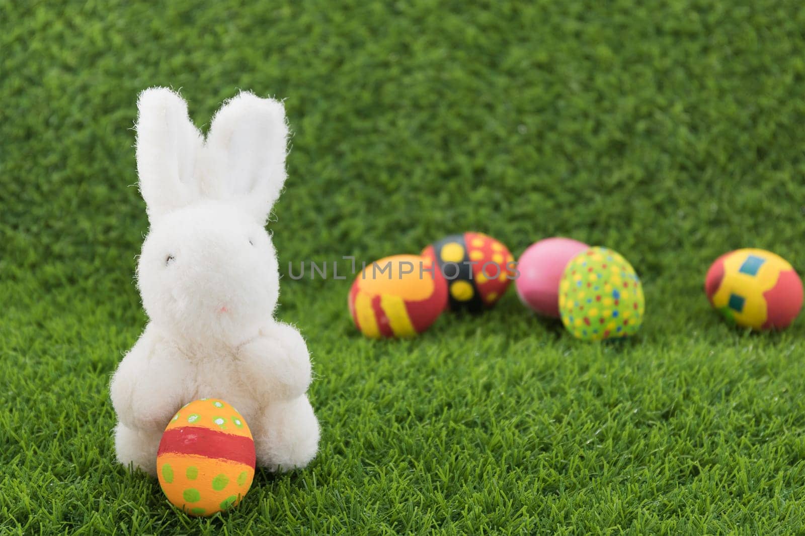 Easter bunny toy and Easter eggs on green grass