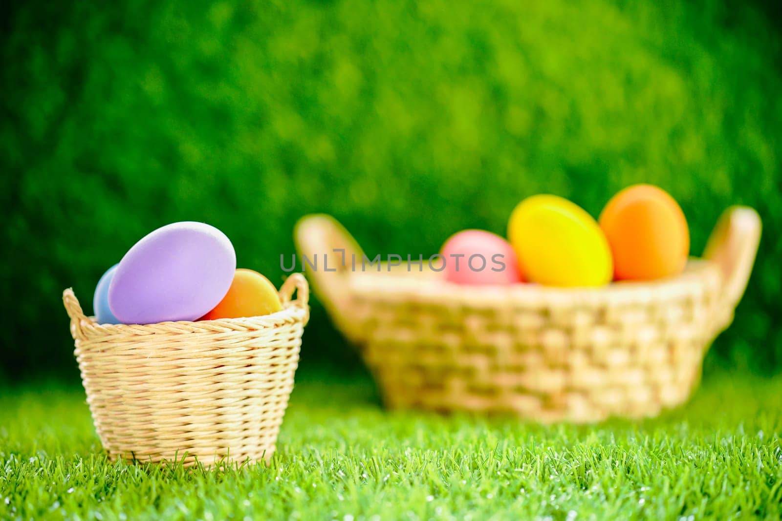 Colorful easter eggs in the basket on green grass background with copy space