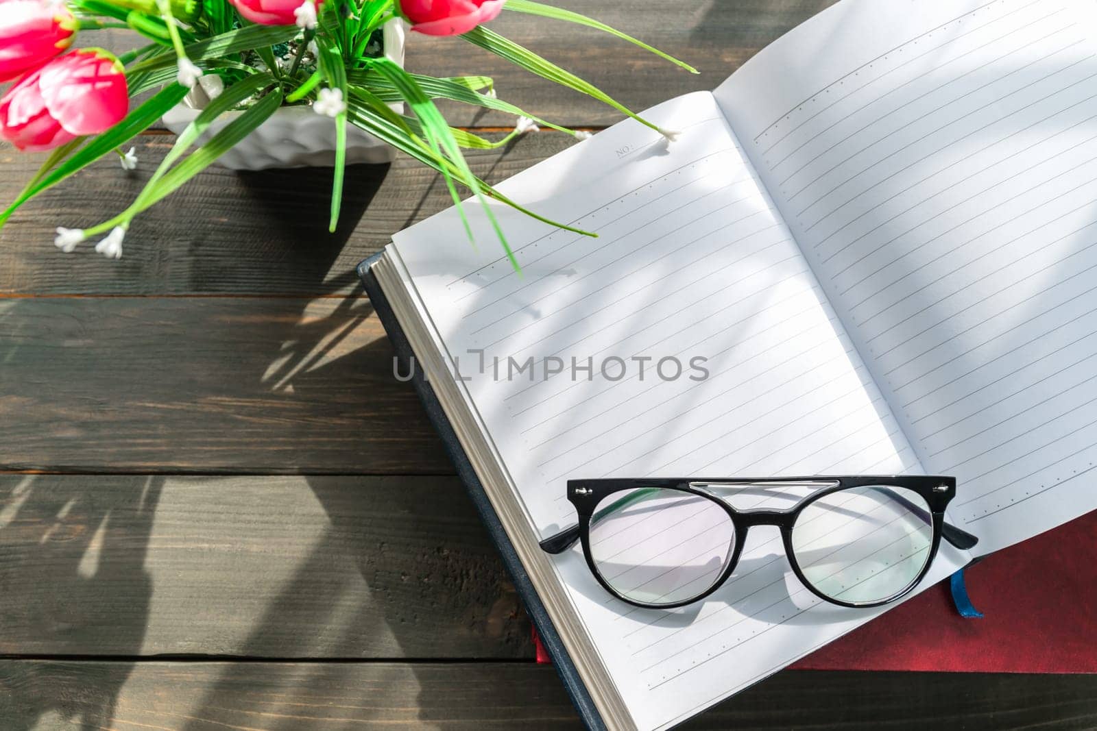 Reading glasses put on open book over wooden table