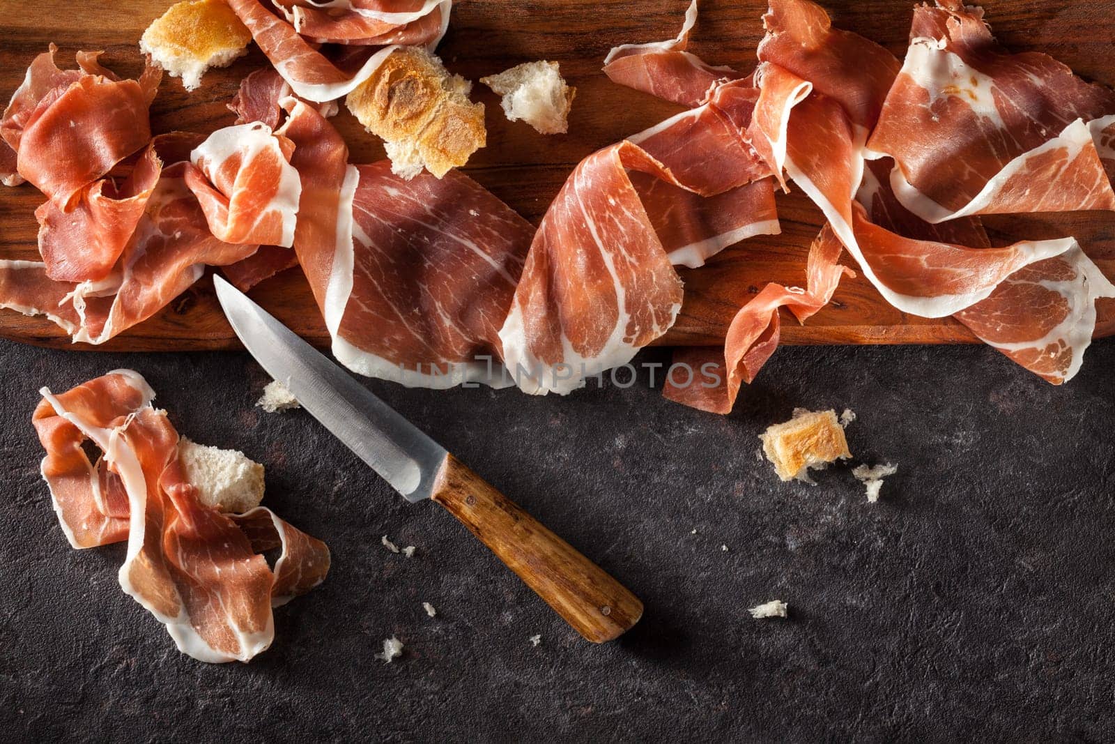 Slices of Prosciutto on dark  background. Top view.
