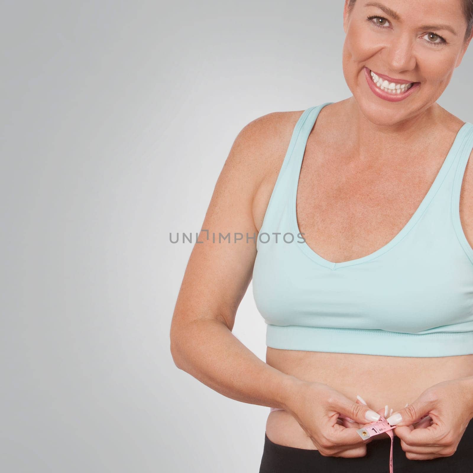 Woman measuring her waist with a tape measure and smiling